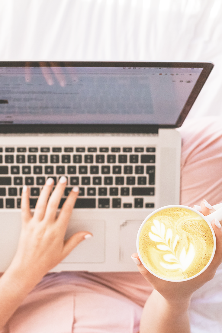 Laptop on woman's lap and her holding a latte