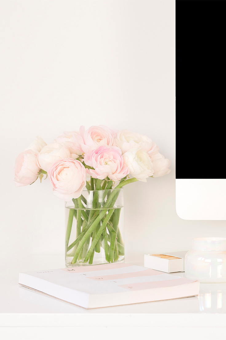 Desk with pink flowers, pink notebook and Apple Mac